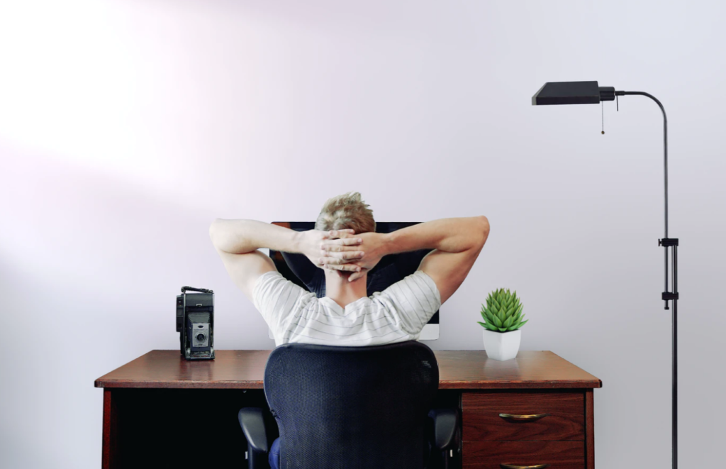 man leaning back in chair, sitting at desk, writing centres