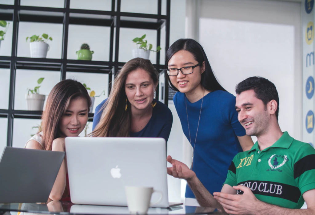 four students around laptop, libraries for group projects