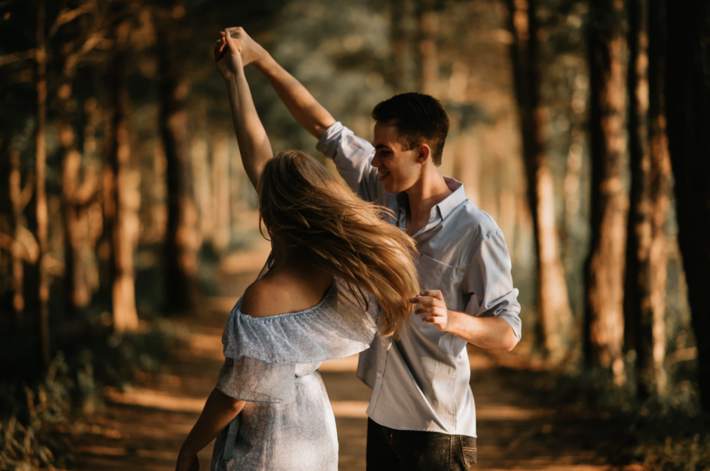 date ideas for students, couple twirling in woods