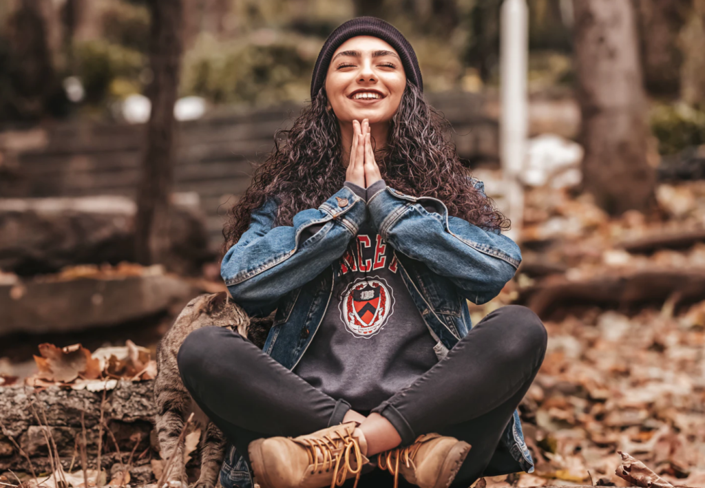 student sitting in the leaves with palms together mindfulness