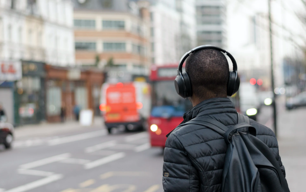 commute etiquette student wearing headphones waiting for bus