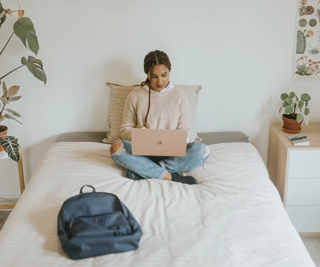 academic support services at mount allison university woman sitting cross-legged on bed with laptop