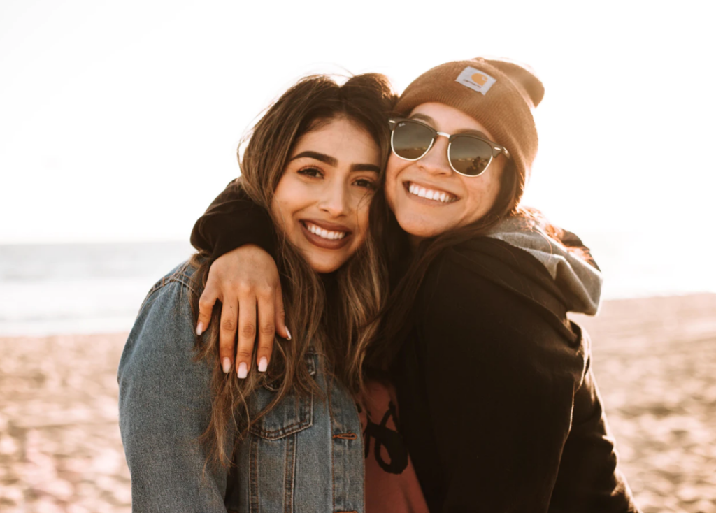 western university clubs two girls smiling at the camera with one arm around the other wearing sunglasses