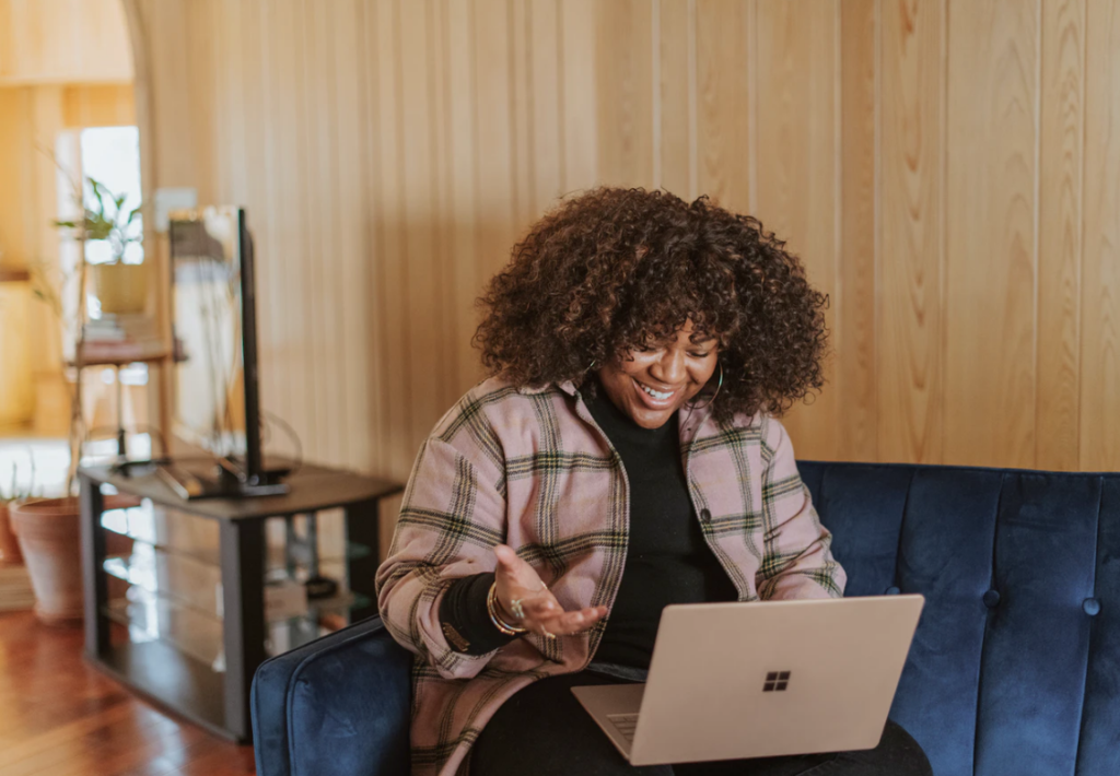 financial assistance at ryerson university , woman wearing a plaid jacket is smiling down at her open laptop resting on her legs