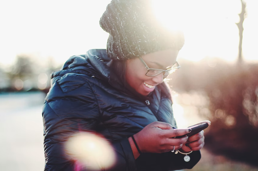 financial aid at concordia university , woman wearing hat and smiling down at her phone