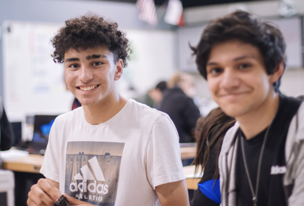 two teenagers sitting in a classroom smiling to the camera, services at fleming college