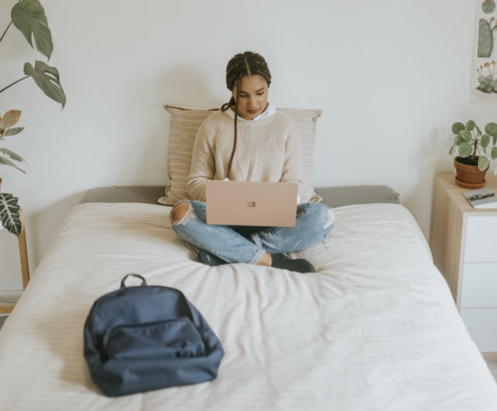 woman sitting on bed with laptop and backpack, university of montreal
