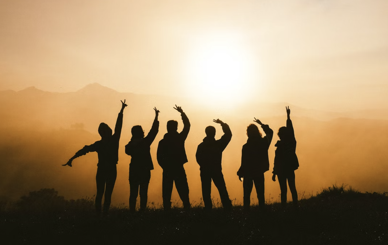 silhouettes of 6 people at sundown waving their arms above their heads, monteal